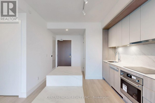 Kitchen with stainless steel dishwasher and oven, white quartz countertops, and light wood cabinetry, adjacent to a central island. - 917 - 6 Greenbriar Road, Toronto