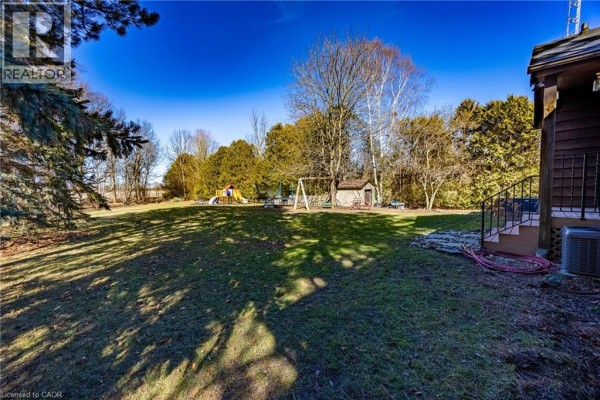Spacious backyard with playground equipment and mature trees - 917 Concession Rd 6, Waterford
