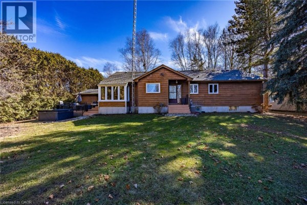 Rear view of the bungalow featuring a patio and landscaped yard - 917 Concession Rd 6, Waterford