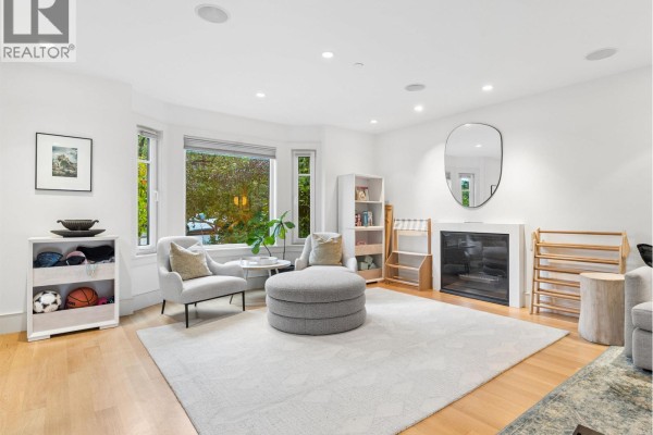 Living room with bay window view of trees, fireplace, and seating area. - 917 W 20th Avenue, Vancouver
