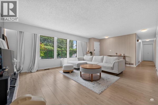 Spacious living room with a sectional sofa, coffee table, white brick fireplace, and three large windows with garden views. - 9171 No. 4 Road, Richmond