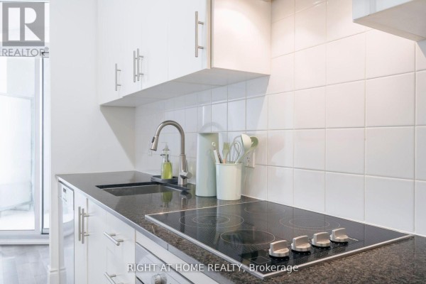 Close-up of the stovetop and sink in the white galley kitchen. - 918 - 23 Glebe Road W, Toronto
