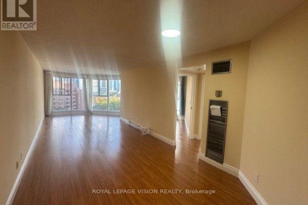 Living room with hardwood floors, large windows offering a city view, and beige walls. - 919 - 222 The Esplanade Street, Toronto