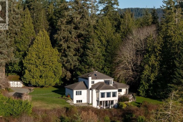 Aerial view of white house surrounded by tall evergreen trees. - 9193 West Coast Rd, Sooke