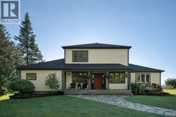 Front view of a two-story light yellow house with a covered porch and stone walkway. - 9193 West Coast Rd, Sooke