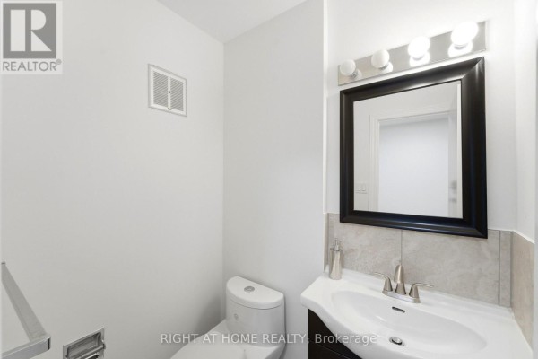Powder room with white toilet, vanity sink, and a black framed mirror. - 92 - 92 St Andrews Drive, Hamilton