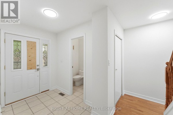 Entryway with double doors, tiled floor, and access to powder room and staircase. - 92 - 92 St Andrews Drive, Hamilton