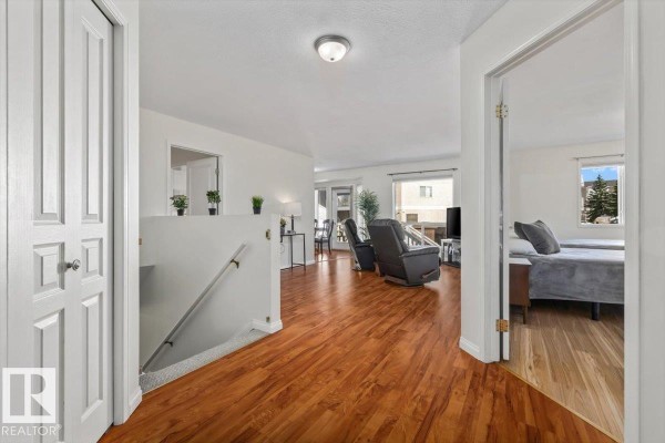 Hallway opening into a living area with wood floors, white walls, and furniture. - #92 13320 124 St Nw, Edmonton