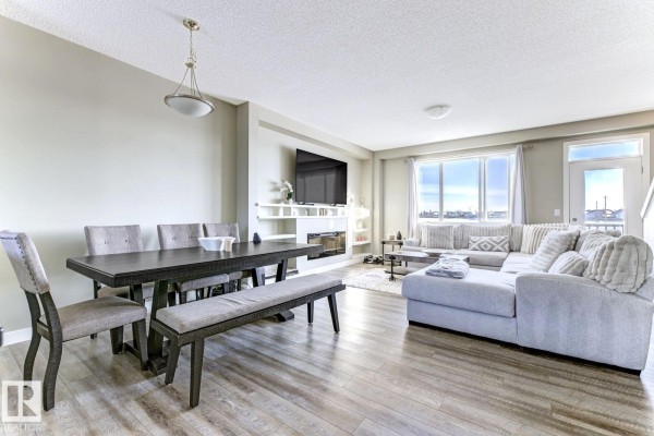 Dining room table with bench and chairs next to a living room with sectional. - #92 16903 68 St Nw Nw, Edmonton
