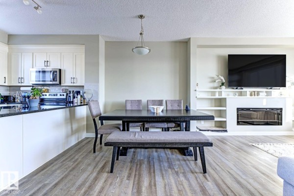 Kitchen with white cabinetry and stainless steel appliances adjacent to dining area. - #92 16903 68 St Nw Nw, Edmonton