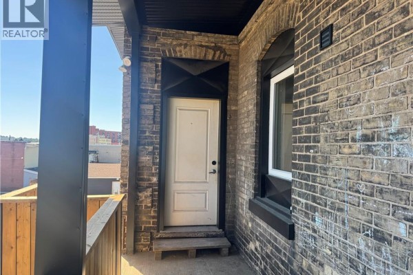 Bedroom with a queen-sized bed, nightstands, and a window overlooking trees. - 92 Alfred Street Unit# 4, Brantford