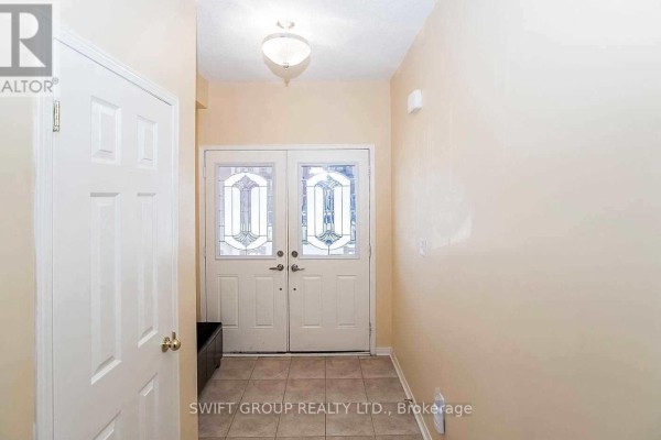 Interior view of a foyer with beige walls, tiled floor, and a double glass-paned door. - 92 Checkerberry Crescent, Brampton