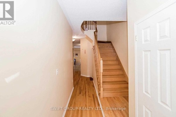 View of a hallway with beige walls, hardwood floors, and a staircase with wooden railings. - 92 Checkerberry Crescent, Brampton