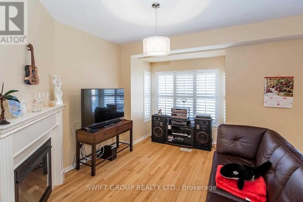 Living room with a fireplace, hardwood floors, white plantation shutters, and a leather sofa. - 92 Checkerberry Crescent, Brampton