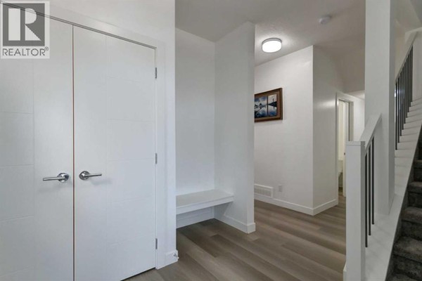 Interior hallway with white walls, dual closet doors, and a built-in bench. - 92 Copperhead Grove Se, Calgary
