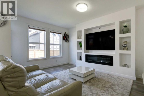 Living room with a white sectional sofa, modern fireplace, and built-in entertainment center. - 92 Copperhead Grove Se, Calgary