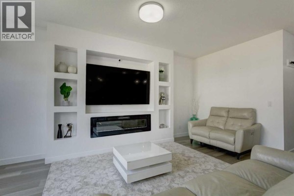 Living room with leather sofas, a white coffee table, and a built-in entertainment center. - 92 Copperhead Grove Se, Calgary
