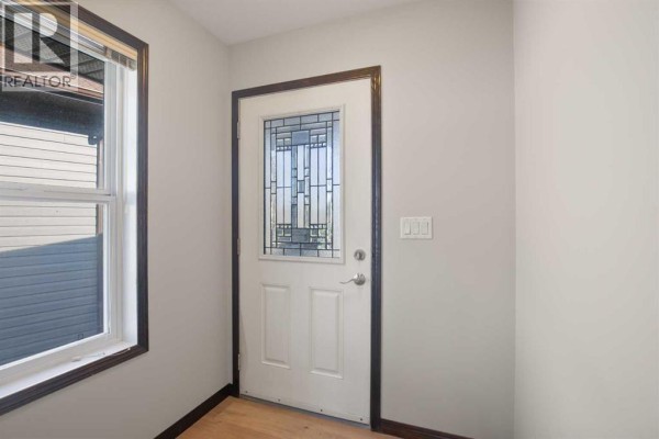 Interior view of the entrance with a white door, glass panels, and beige walls. - 92 Ireland Crescent, Red Deer