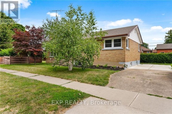 Side exterior of a brick bungalow with a driveway, walkway, and lawn. - Lower - 92 Margery Avenue, St  Catharines