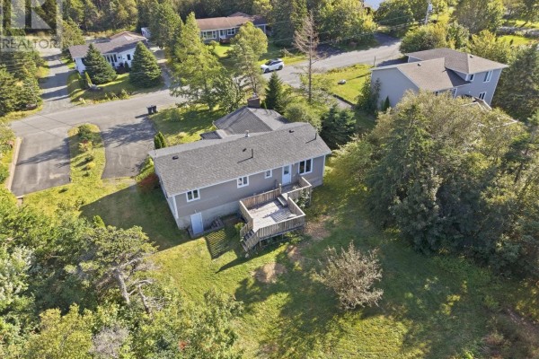 Aerial view of the house's backyard with a wooden deck and surrounding trees and neighboring homes. - 92 Quigleys Lane, Torbay