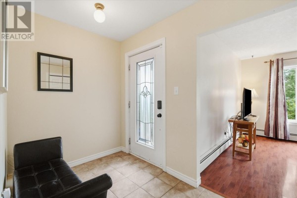 Entrance hallway with beige walls, tile floor, glass-paneled front door, and black leather bench. - 92 Quigleys Lane, Torbay