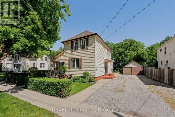 Side exterior view of the house, driveway, and detached garage on a sunny day. - 92 Saint Arnaud Street, Port Colborne