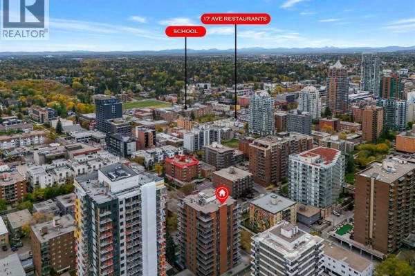 Aerial view highlighting nearby amenities like a school and restaurants, with mountain views. - 920, 540 14 Avenue Sw, Calgary