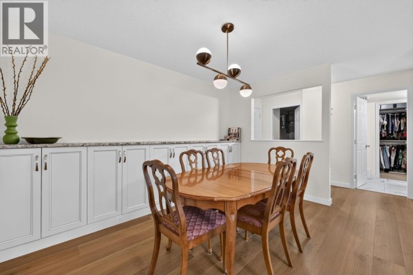 Dining room with a wooden table, chairs, built-in cabinets, and an open doorway to a walk-in closet. - 920 Glenwood Avenue Unit# 208, Kelowna
