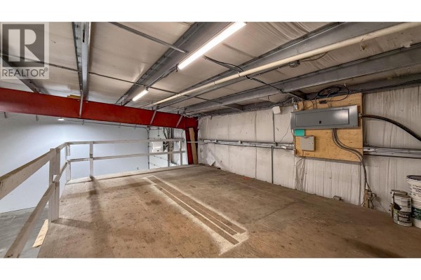 Aerial view of a commercial property featuring several industrial buildings, storage containers, and vehicles. - 9207 James Avenue Unit# 103, Summerland