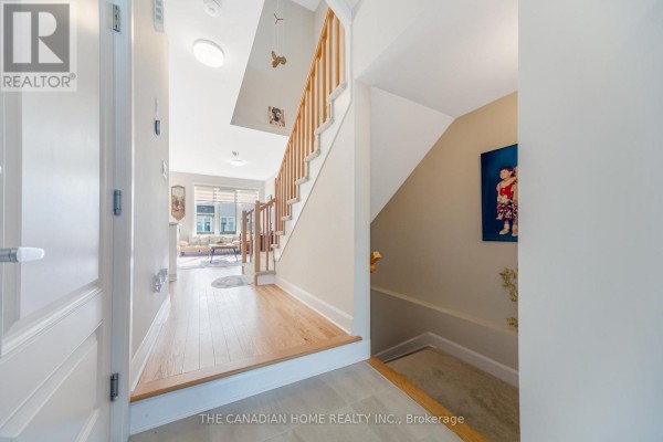 Living room with hardwood floors, patterned rug, wooden furniture, and large windows. - 921 Clarkia Street, Ottawa