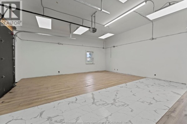 Interior commercial space with roll-up door, wood-look vinyl, and tiled flooring. - 921 Tecumseh Road West Unit# Front, Windsor