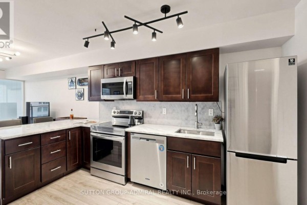 Modern kitchen with dark wood cabinets, stainless steel appliances, and granite countertops. - 922 - 111 Elizabeth Street, Toronto