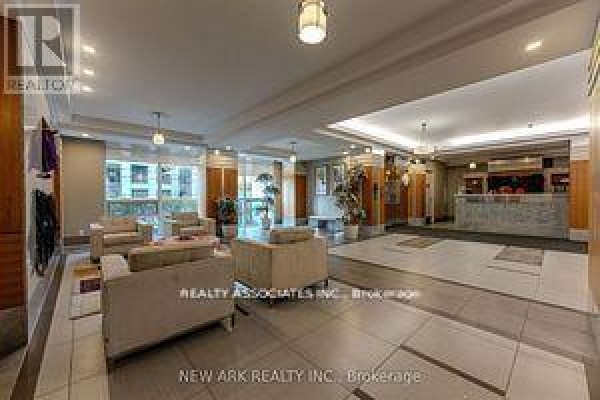 A spacious, well-lit apartment building lobby with seating areas and a reception desk. - 922 - 30 Clegg Road, Markham