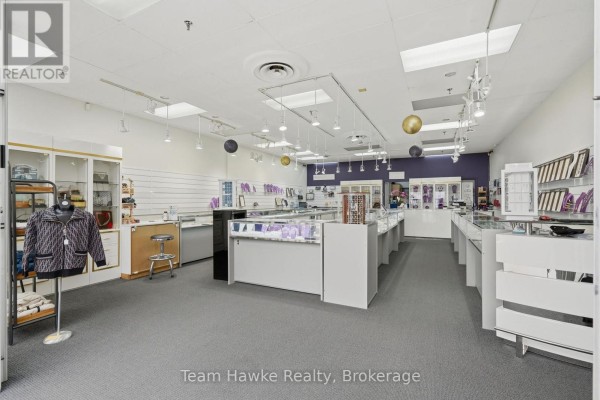 Retail jewelry store interior with display cases, purple accent wall, and clothing mannequin. - 9225 County 93 Road, Midland