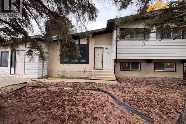 Close-up of the house exterior showing textured stucco and white siding with black trim. - 924 19b Avenue, Coaldale