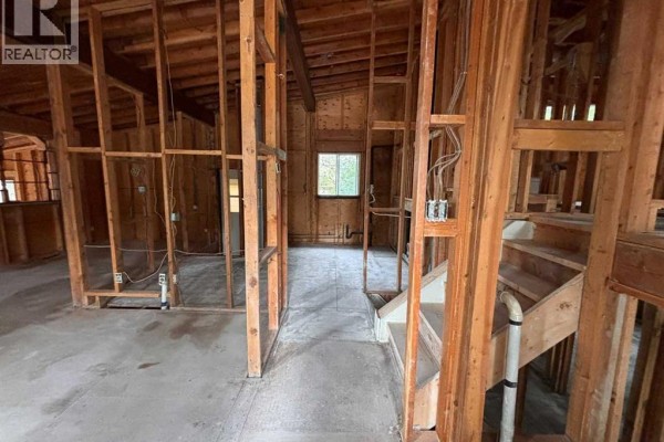 Interior view of a room under renovation, showing exposed wooden studs and concrete floor. - 924 19b Avenue, Coaldale