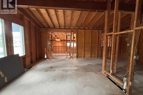 Unfinished interior room with exposed ceiling joists, wooden studs, and concrete floor. - 924 19b Avenue, Coaldale