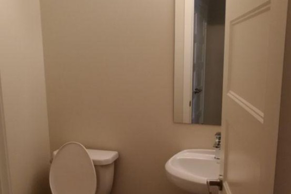 Powder room with a white toilet, small sink, and wall-mounted mirror. - 924 Georgetown Drive, London North