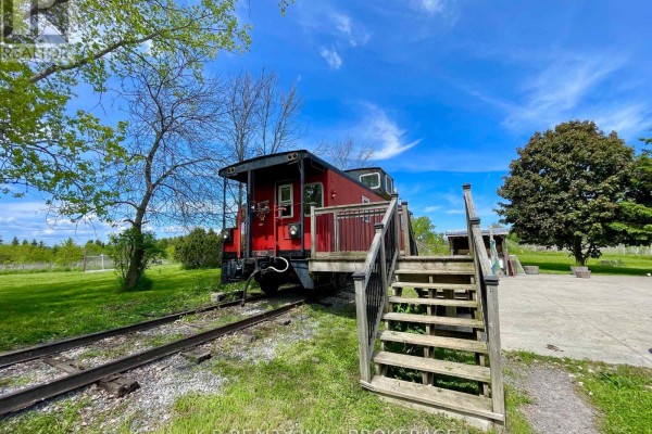 Red caboose on train tracks with wooden deck and stairs - 9261 Loyalist Parkway Greater Napanee