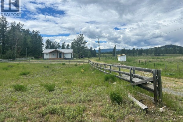 Laundry area with black Samsung washer and dryer, water heater, and blue water filter. - 9275 Pighin Road, Cranbrook