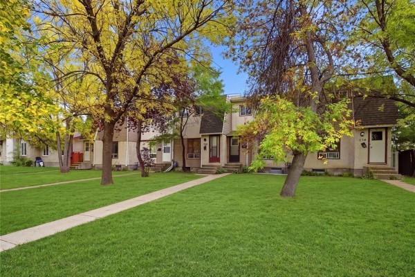 A row of beige and brown multi-family townhouses with trees and green grass in front. - 928 Greencrest Avenue, Winnipeg