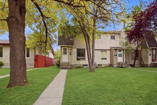 A concrete walkway leads to the entrance of a beige two-story multi-family home with brown siding. - 928 Greencrest Avenue, Winnipeg