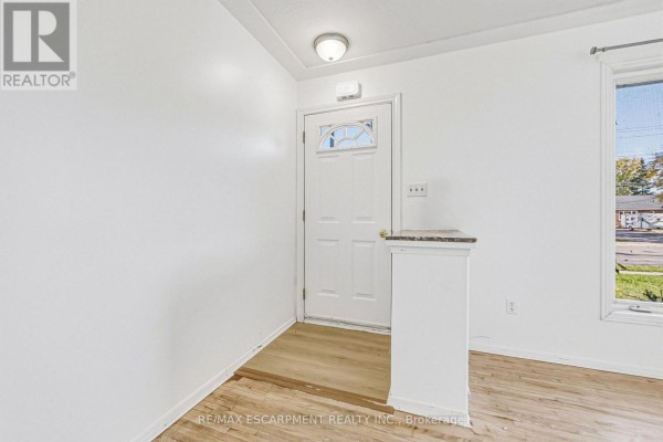 Empty living room featuring large bay window and hardwood flooring - 928 Upper Gage Avenue, Hamilton