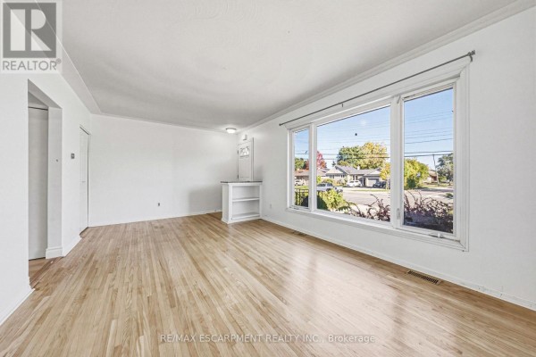 Living room with brown leather sofas, dining table, and wall-mounted TV - 928 Upper Gage Avenue, Hamilton