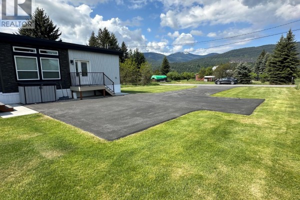 Outdoor concrete patio with a dark metal gazebo and draped curtains. - 928 Waterloo Crescent, Castlegar