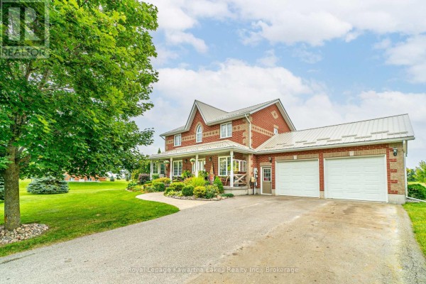 Side view of a red brick home with a metal roof, covered porch, and driveway. - 929 Eldon Road, Kawartha Lakes