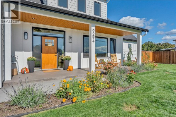 Close-up of front entrance with a wooden door, glass sidelights, and porch seating. - 9294 Jones Flat Road, Summerland