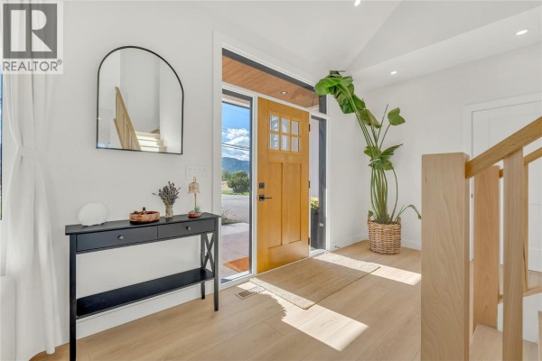 Interior entryway with light wood floors, a console table, large plant, and open doorway. - 9294 Jones Flat Road, Summerland