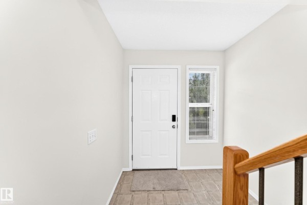 Interior view of the front entrance with a white door, window, and light grey walls. - #93 230 Edwards Dr Sw, Edmonton