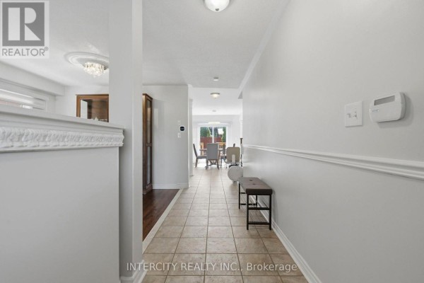 Interior hallway with tiled floors, white walls, crown molding, and a bench with dark wood flooring. - 93 Chalone Crescent, Vaughan